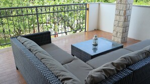 Un balcon agrémenté de meubles en osier, d’une table en verre et d’une lanterne.
