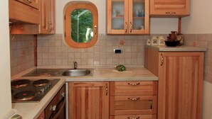 A kitchen with wooden cabinets, a built-in stove, a sink, and a window with a view of greenery. - Holiday Home in Brod na Kupi by River Kupa (Delnice)