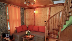 A cozy room with a wooden staircase, a sofa with red cushions, and a small table with a radio and flowers. - Holiday Home in Brod na Kupi by River Kupa (Delnice)