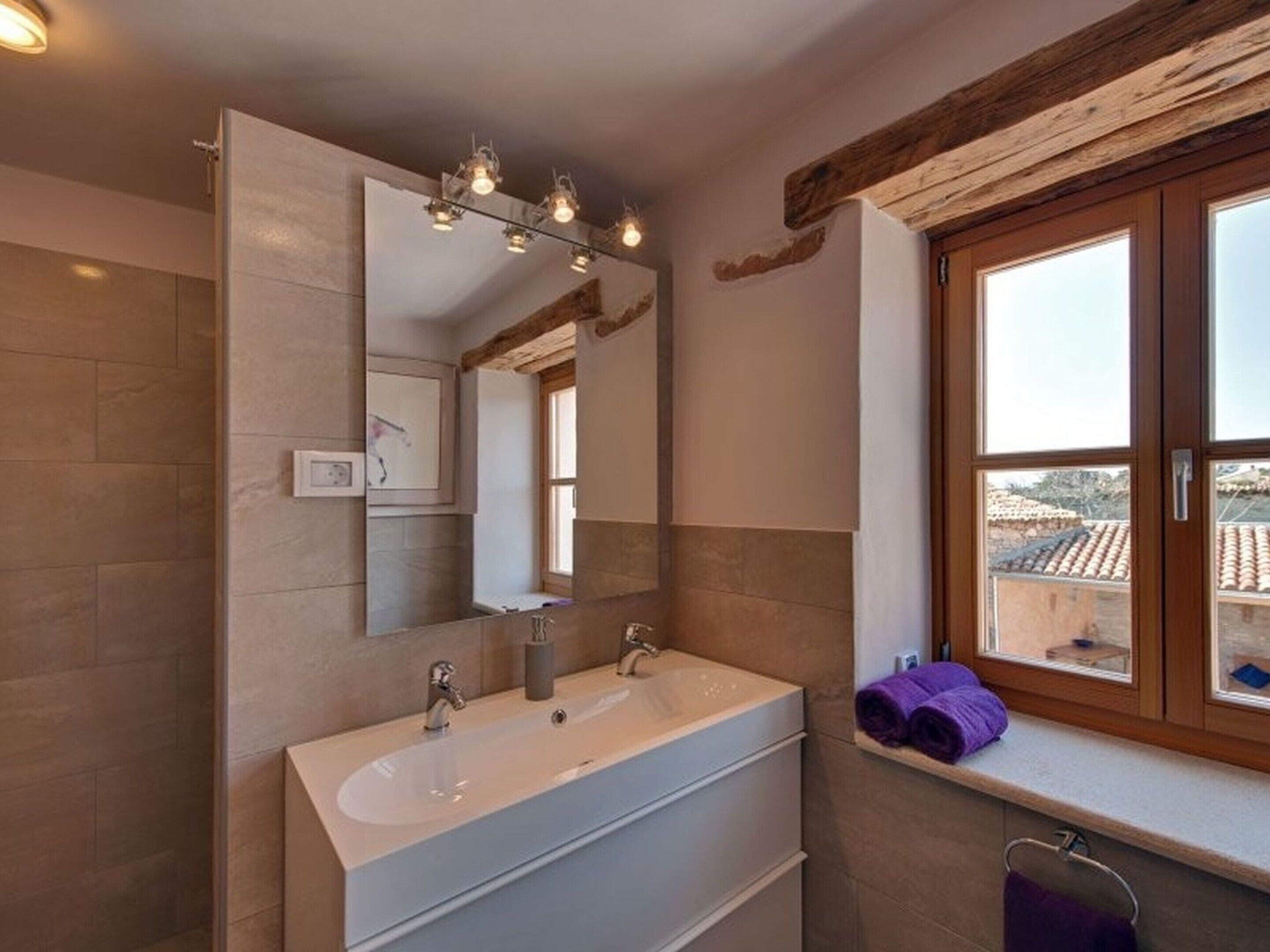 Un baño con un espejo grande, un lavabo y una ventana que ofrece vistas al exterior.