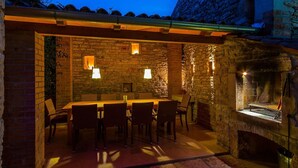 An outdoor dining area with stone walls, a brick fireplace, and a table set for six. - Beautiful Villa Consisting of two Houses With Private Pool, Near Pula and Beach (Liznjan)