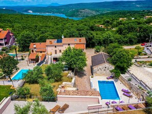 A villa with multiple pools, a water slide, and a view of a lake and mountains. - Villa in Rakalj Near Secluded Beaches (Marcana)