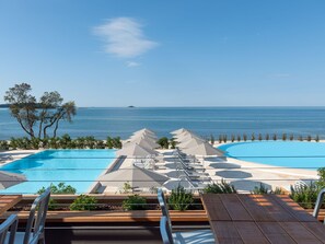 A pool area with two swimming pools, lounge chairs, and umbrellas, overlooking a beach and the sea. - Comfortable Holiday Home With a Microwave, Near Rovinj (Rovinj)
