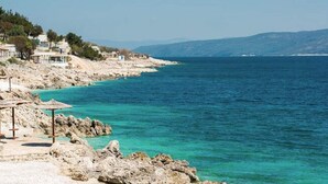A coastal hotel with rocky terrain, clear blue waters, and a view of distant mountains. - Holiday Home in Labin With Private Pool (Labin)