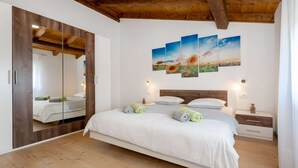 A bedroom with a wooden ceiling, a large bed with white bedding, a wooden wardrobe, a mirror, and a wall with three paintings. - Holiday Home in Labin With Private Pool (Labin)