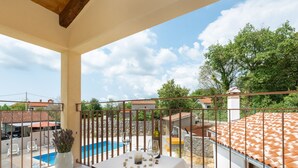 A balcony with a pool, a table with a white tablecloth, and a potted plant. - Holiday Home in Labin With Private Pool (Labin)