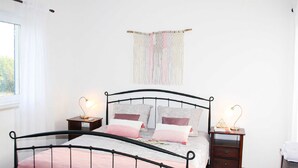 Una camera da letto con un telaio letto in metallo, due comodini, un arazzo a parete e una finestra con tende.