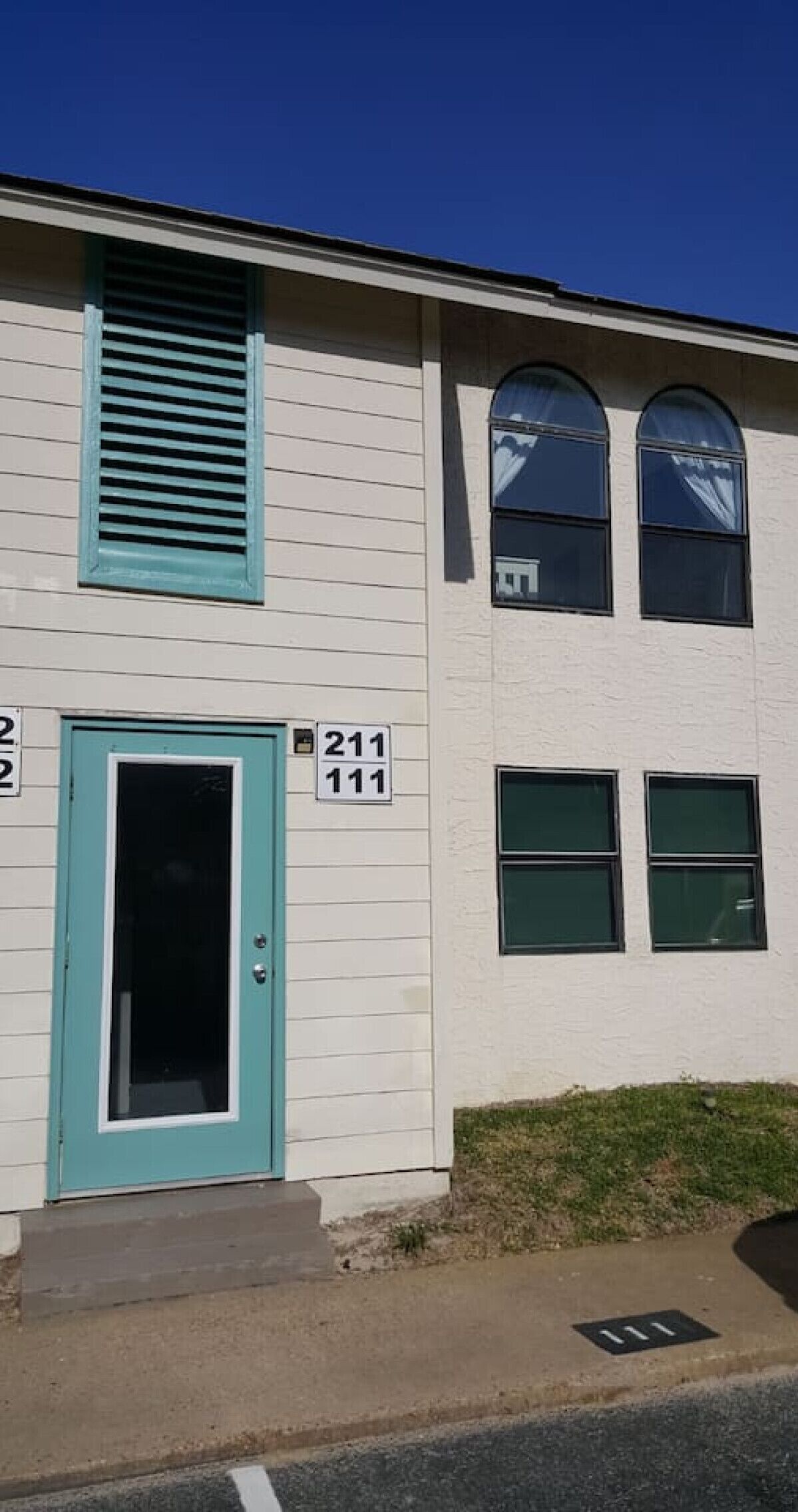A two-story building with a teal door and windows.