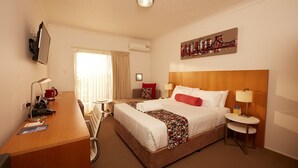 A hotel room with a bed, desk, chair, and a painting on the wall. - Private Room Brisbane (Spring Hill)