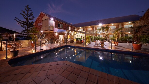A hotel with a swimming pool, outdoor seating, and a bar area. - Private Room Brisbane (Spring Hill)