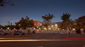 A hotel with a gated entrance, a parking area, and a street with cars. - Private Room Brisbane (Spring Hill)