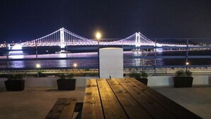 Una mesa de madera con plantas en macetas, con vistas a un puente iluminado de noche.