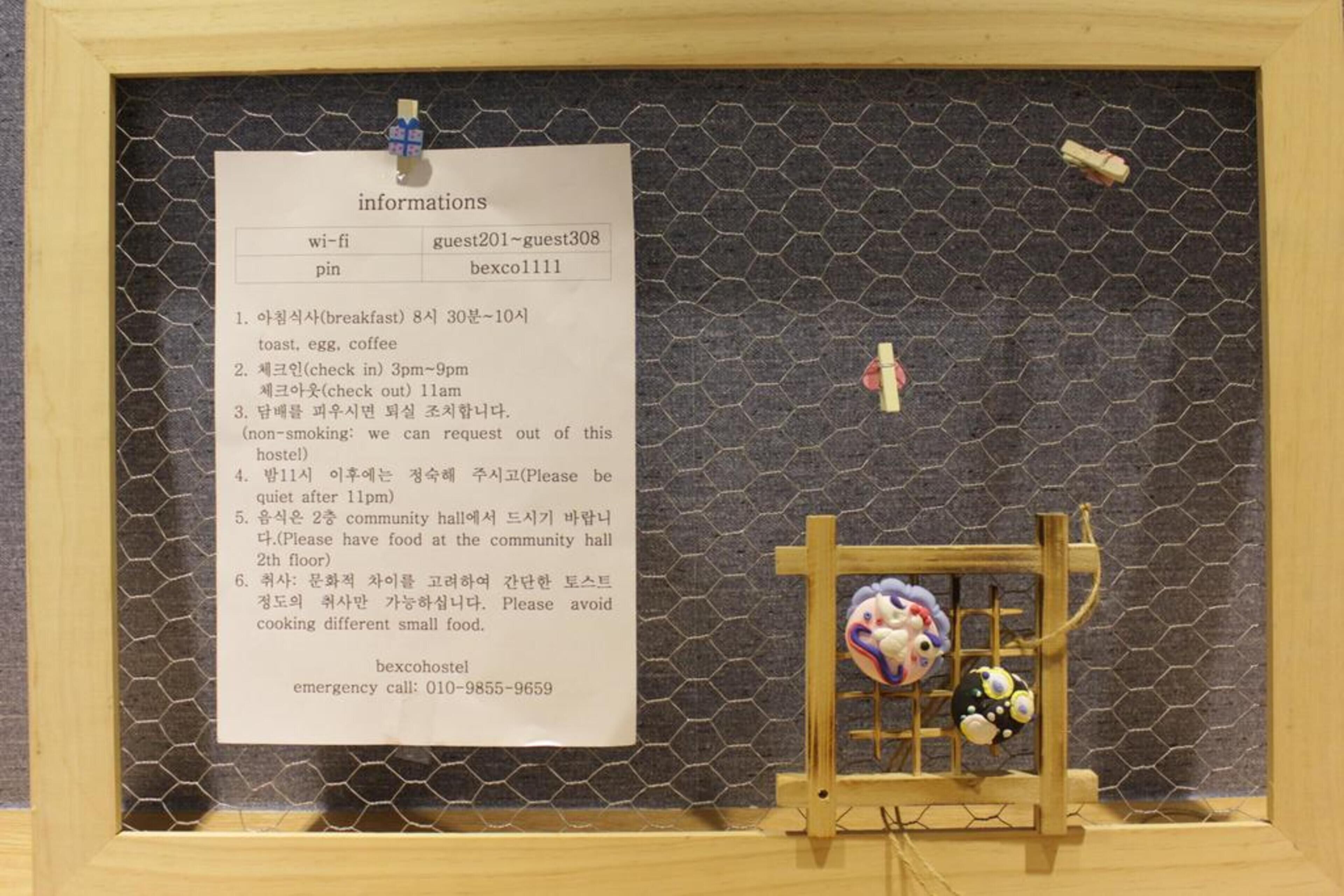 A bulletin board with a list of information including Wi-Fi details, guest numbers, and emergency contact.