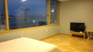 Habitación de hotel con un ventanal grande, una cama, un televisor y una mesita.