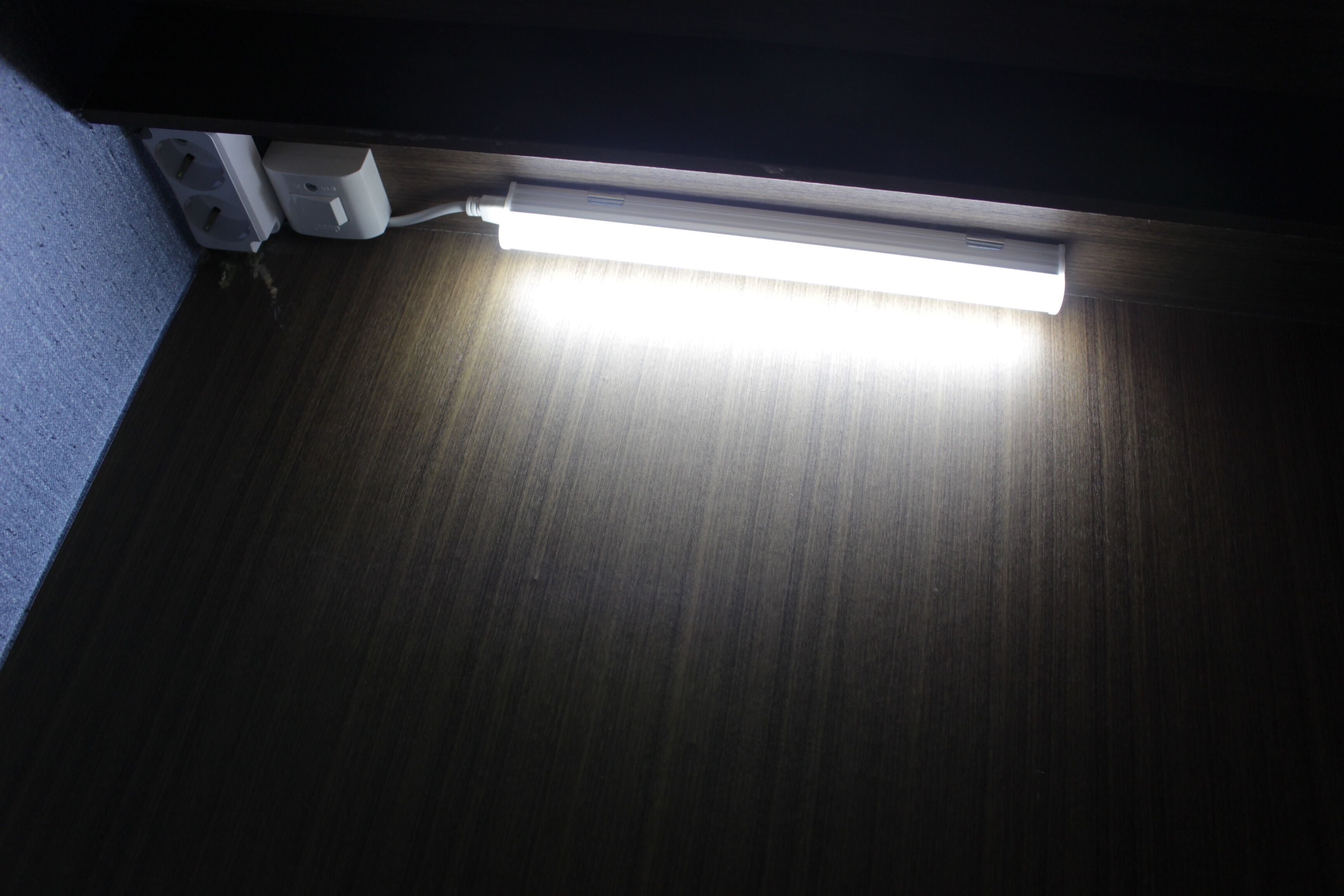 Eine Leuchtstofflampe unter einer dunkel gefärbten Decke.