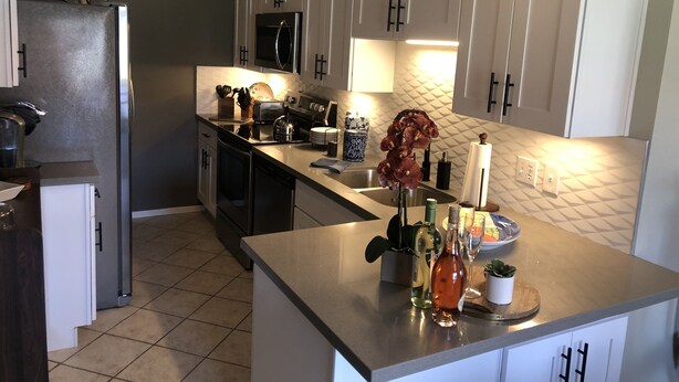 A modern kitchen with white cabinets, stainless steel appliances, and a central island.