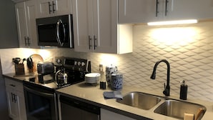 A modern kitchen with stainless steel appliances, white cabinetry, and a geometric backsplash.