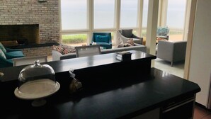Une cuisine moderne dotée d’un plan de travail noir, d’un îlot central avec une plaque de cuisson en verre et d’un mur recouvert de briques.