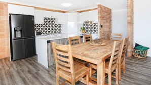 A compact kitchen with a refrigerator, white cabinets, and a patterned backsplash. - Illawong 7 (Mooloolaba)