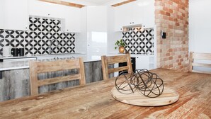 A modern kitchen with white cabinets, black and white patterned backsplash, and a brick accent wall. - Illawong 7 (Mooloolaba)