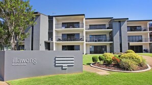 A modern apartment building with multiple balconies, a well-maintained lawn, and a sign indicating it is located at 48 Parkyn Parade. - Illawong 7 (Mooloolaba)