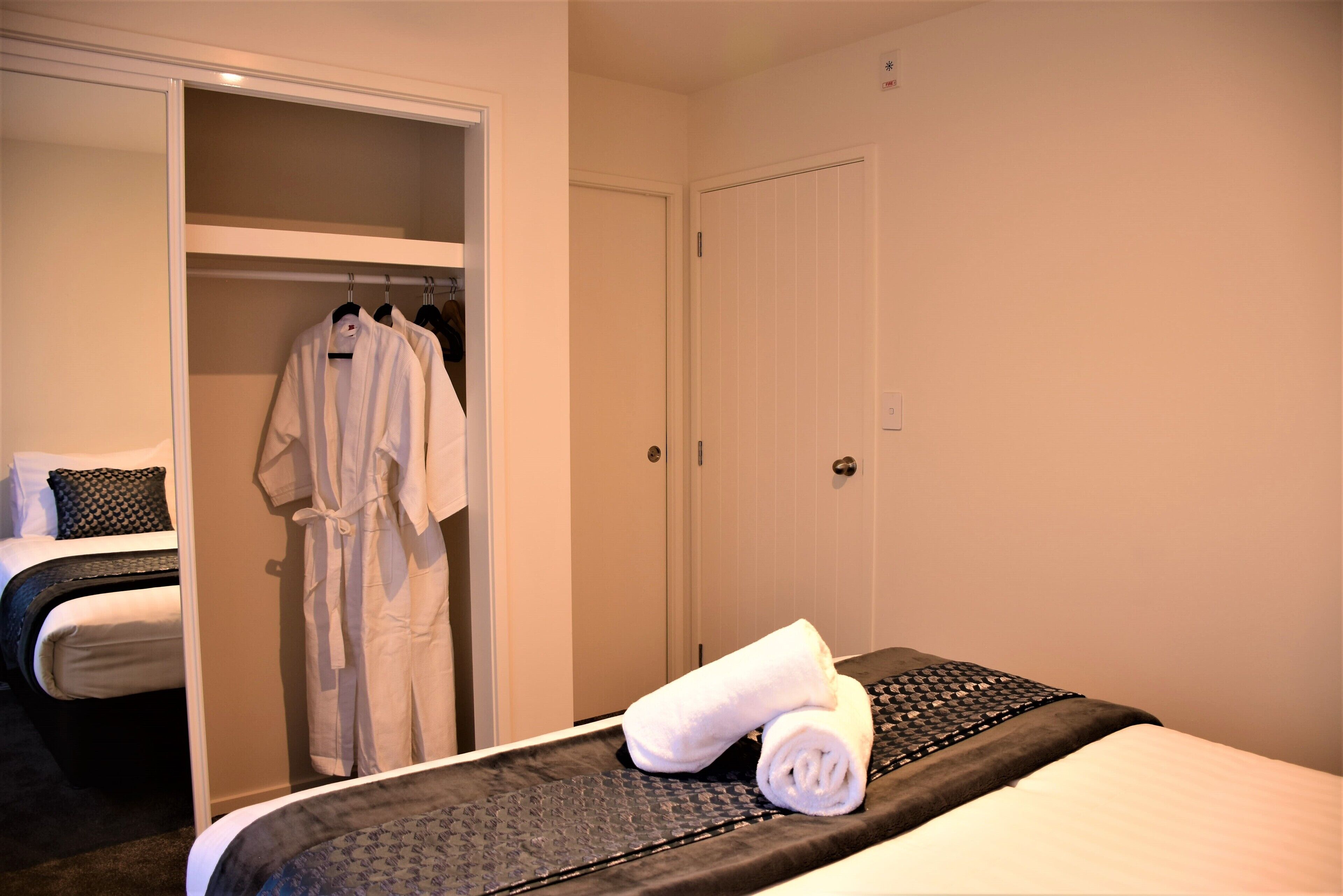 A hotel room with a bed, a robe hanging on a rack, and a closed door.