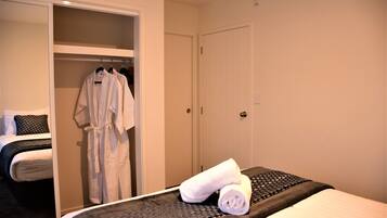 A hotel room with a bed, a robe hanging on a rack, and a closed door.