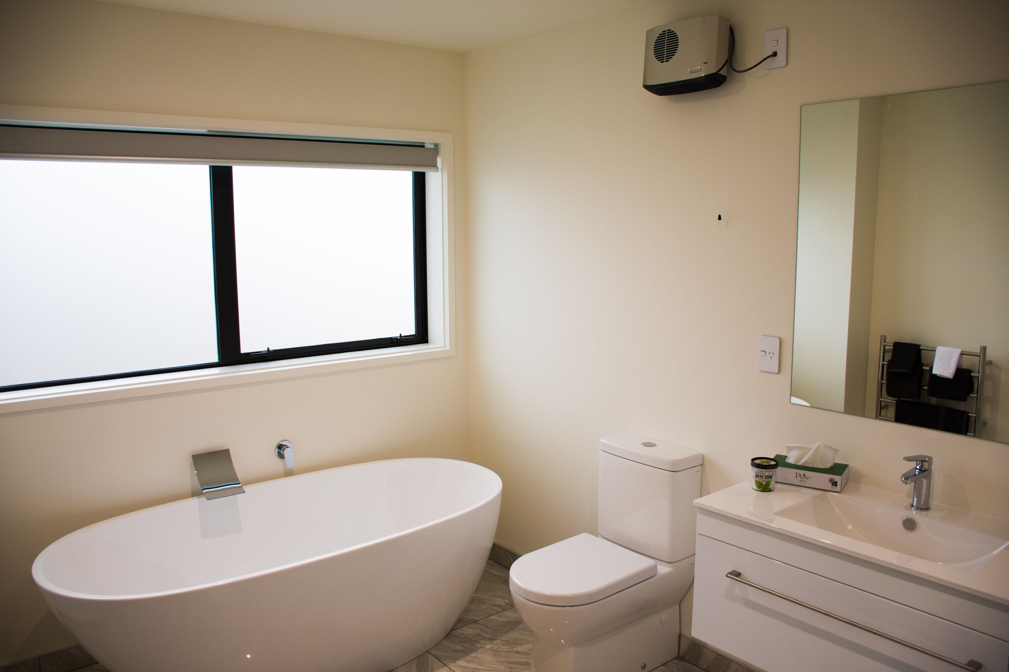 A bathroom with a freestanding bathtub, a toilet, a sink, and a mirror.