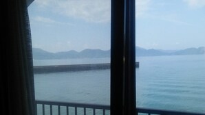 Vista desde un balcón con barandilla, sobre un cuerpo de agua tranquilo y montañas distantes.