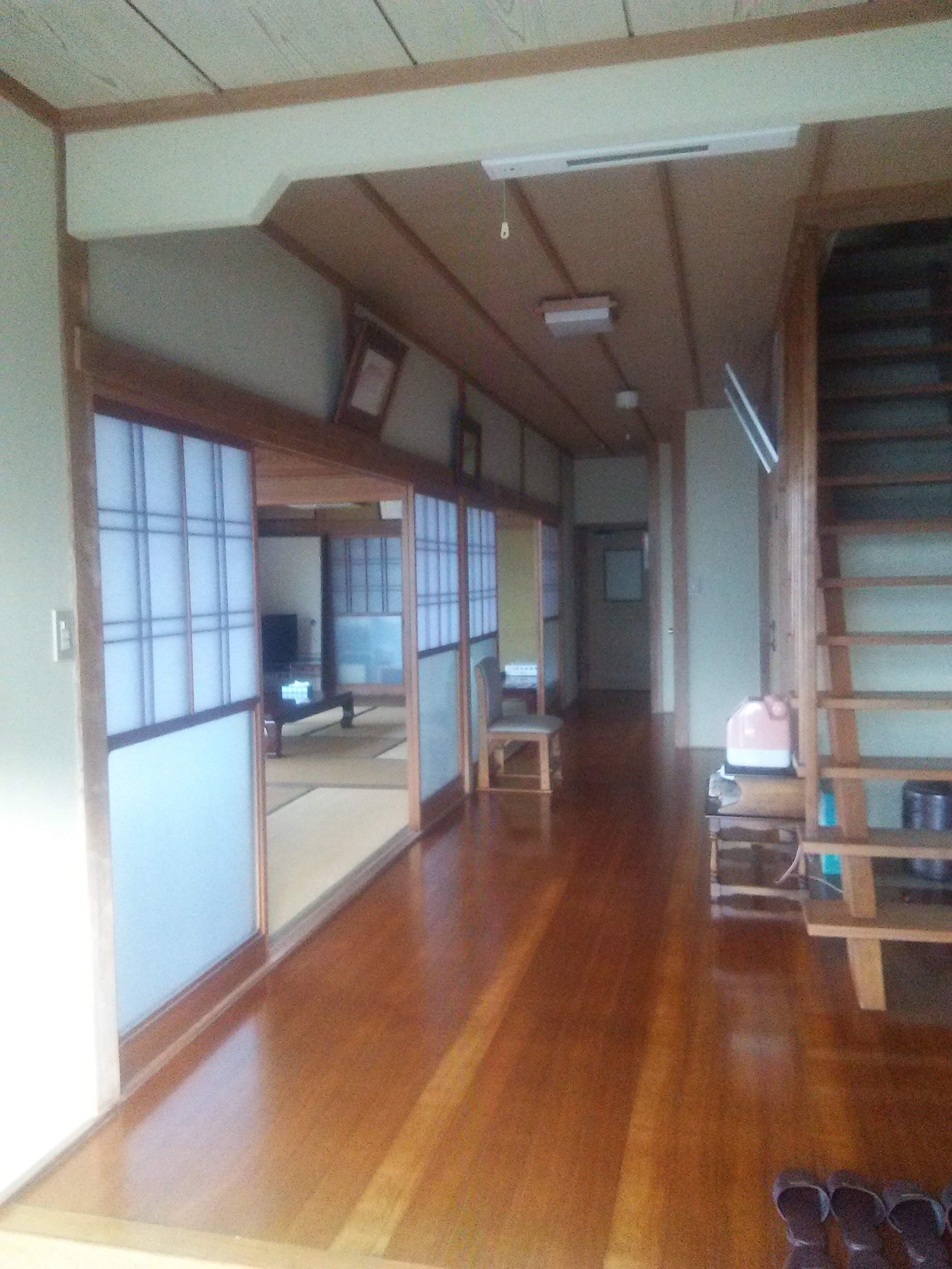 Une pièce de style japonais traditionnel, avec un sol recouvert de tatamis, des portes coulissantes et une petite étagère en bois sur laquelle se trouve une bouilloire.
