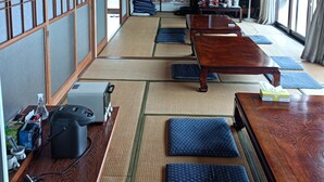 Una habitación tradicional japonesa con tatamis, una mesa de madera y un televisor.