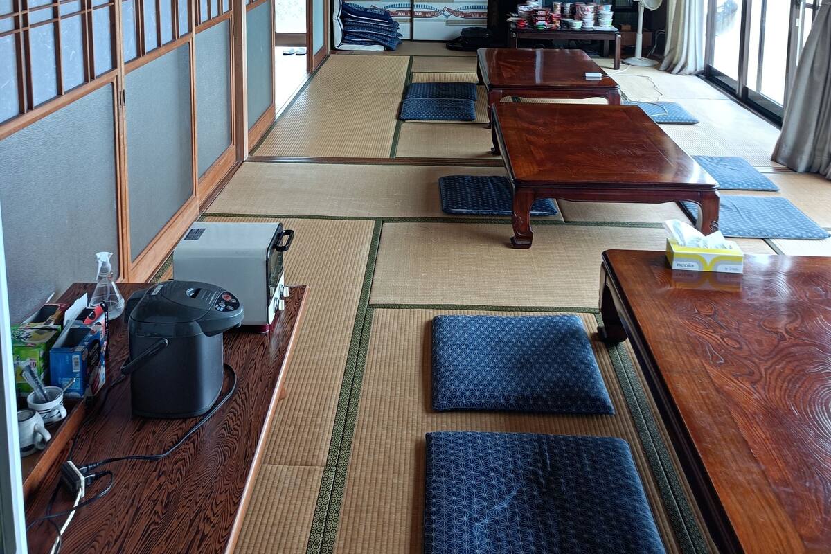 Een traditionele Japanse kamer met tatami vloermatten, een houten tafel en een televisie.