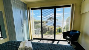 Ein Hotelzimmer mit Bett, Stuhl und Blick ins Freie.