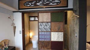 Een traditionele Japanse badkamer met een houten schuifdeur, een toilet en een wastafel.