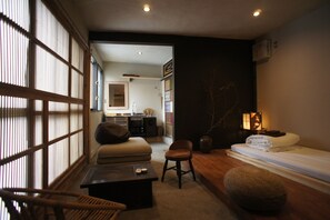 Et traditionelt japansk værelse med tatamimåtter, et lavt træbord, en polstret bænk og en futon-madras.