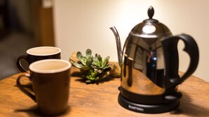 A wooden table with two coffee cups, a metal coffee pot, and a small plant. - Yoshinaga Apartment 103 (Tokyo)