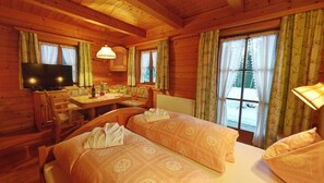 Cozy cabin-style room with two beds, a desk, and a dining table.