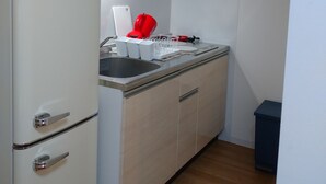 A compact kitchen with a microwave, sink, and cabinets. - Lyon Doll Shinjuku Gyoen 401 (Tokyo)