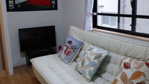 A room with a white sofa, a flat-screen TV, and a wall-mounted picture of a mountain. - Lyon Doll Shinjuku Gyoen 401 (Tokyo)