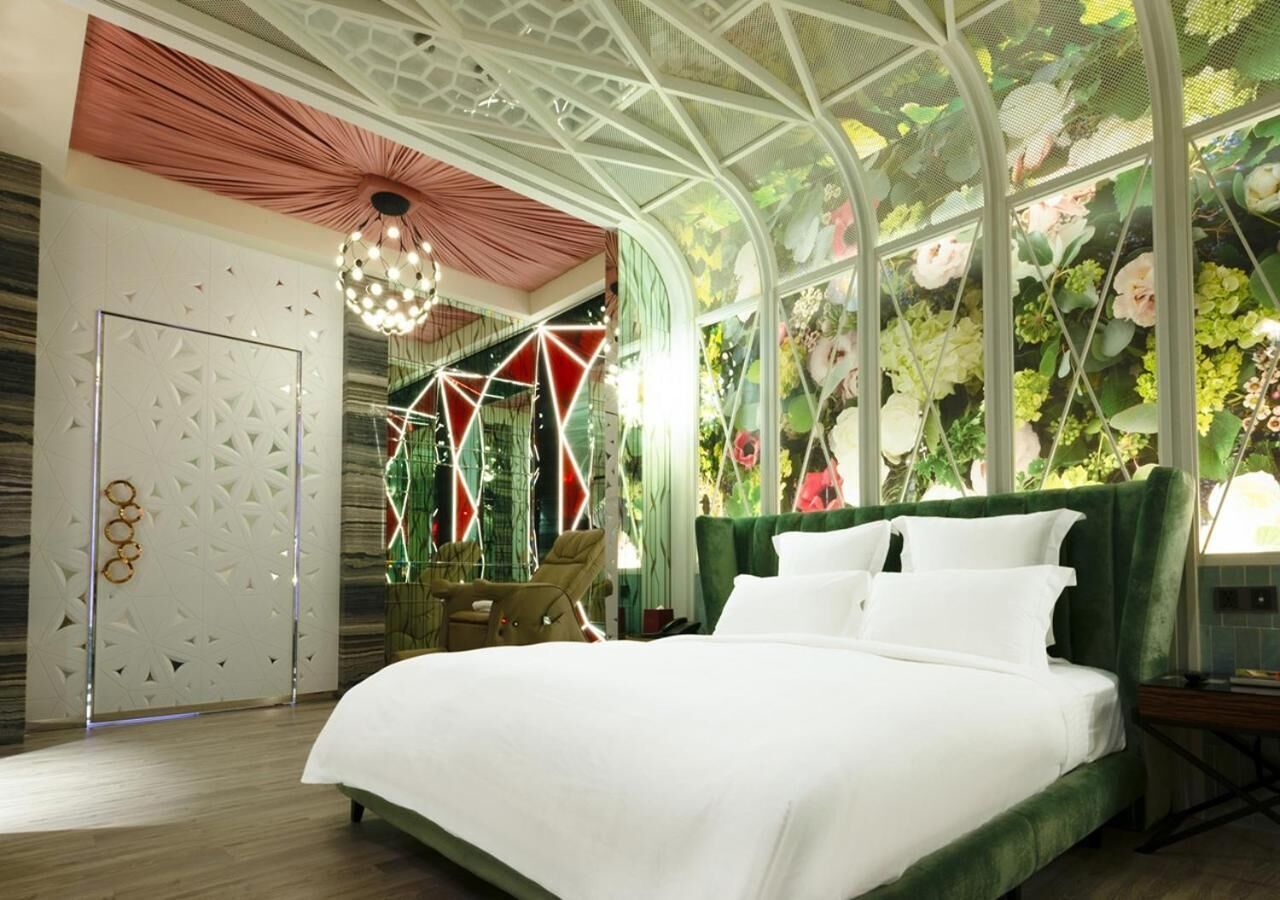 A modern bedroom with a large bed, a hanging chair, and a decorative ceiling.