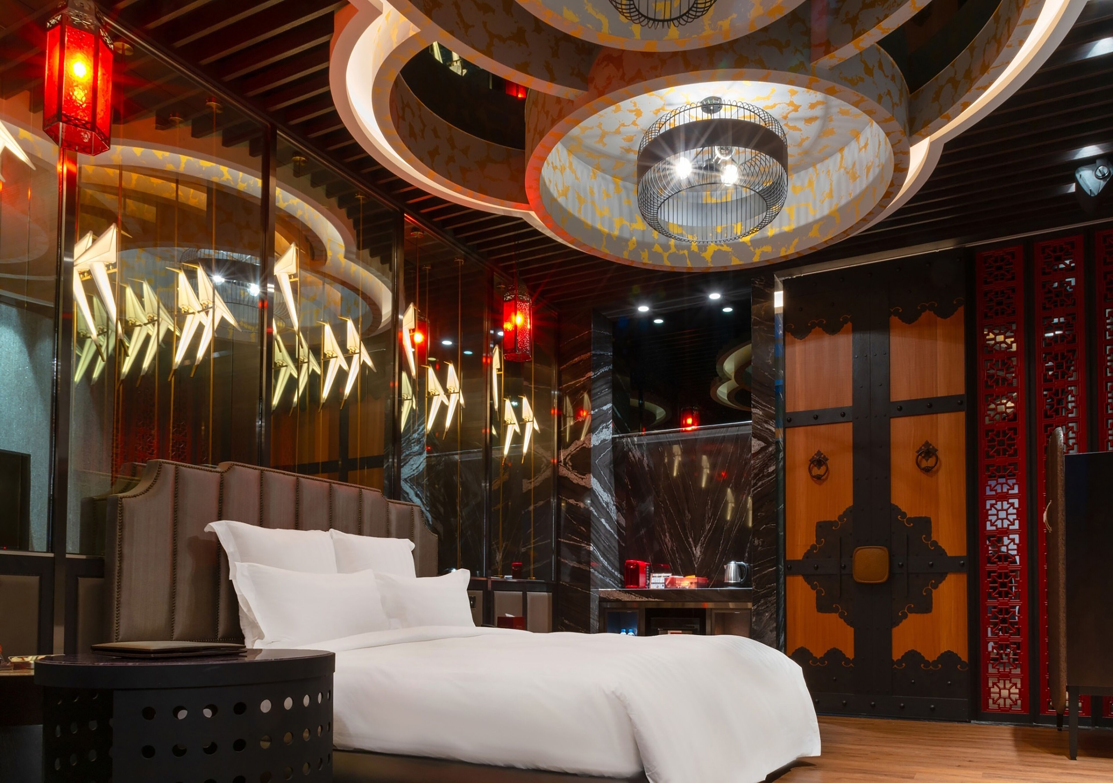 Een moderne hotelkamer met een groot bed, een ronde tafel en een uniek plafondontwerp.