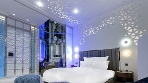 A modern hotel room with a large bed, a seating area, and a view of the cityscape through large windows. - Royal Group Motel Jhong Hua Branch (Kaohsiung)