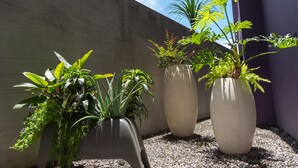 Three large potted plants against a concrete wall with a clear sky. - Royal Group Motel Jhong Hua Branch (Kaohsiung)