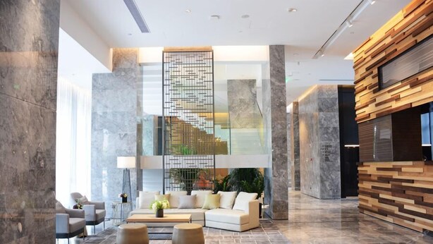 A modern lobby with a central seating area, a staircase, and a reception desk. - Wassim Hotel (Shanghai)