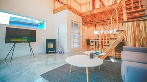 Ein großzügiger Wohnbereich mit einem großen Flachbildfernseher, einer Treppe mit Holzwangen und einem modernen Design.