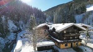 Een ruime houten chalet met meerdere balkons, omringd door sneeuwbedekte bomen en een berg op de achtergrond.