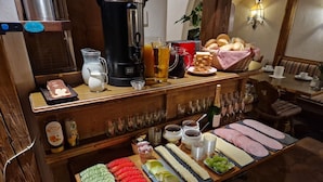 Een ontbijtbuffet met diverse gerechten, een koffiezetapparaat en een fles wijn.