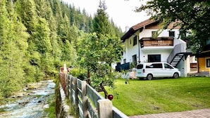 Uitzicht op een rivier, met een houten hek, een witte auto en een gebouw met een balkon.