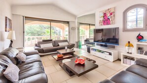 Ein modernes Wohnzimmer mit Sofa, Couchtisch, Fernseher und einem Balkon mit Glasüren.