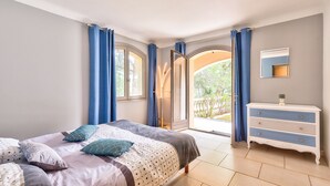 Ein Schlafzimmer mit Bett, Kommode und Blick ins Freie.